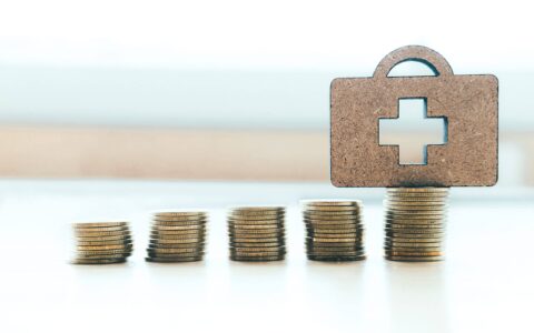 Health insurance copyspace background idea concept. Coin stacks and medical bag wood.